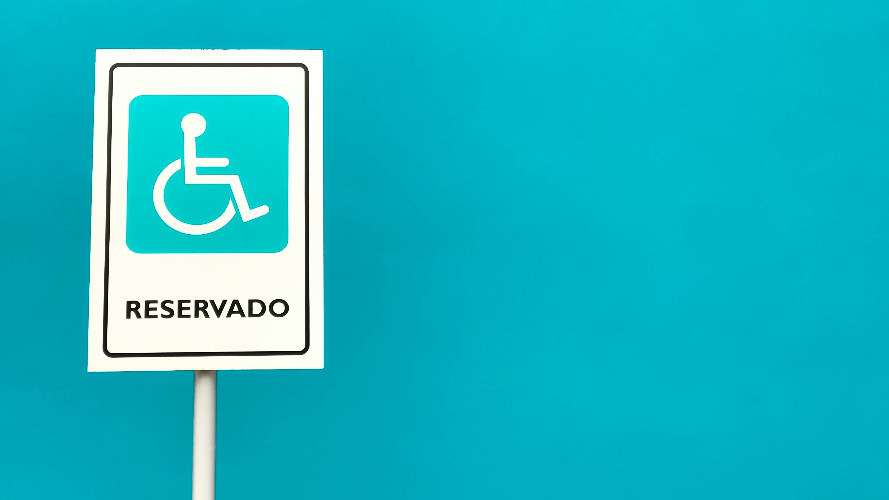 Sign indicating reserved for someone with a physical impairment, in Spanish, on a blue background.