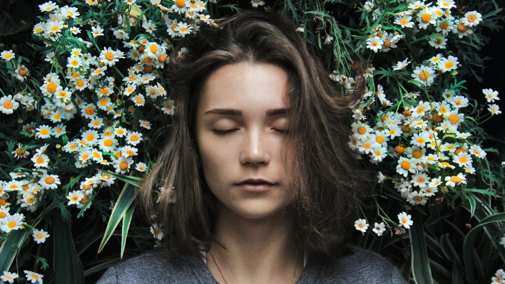 Woman with head laid down on a bed of dasies.